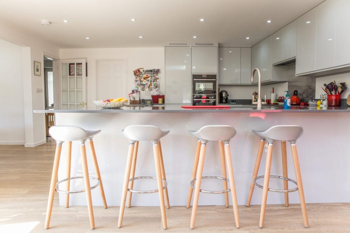 Gloss grey handleless kitchen with large island, dark worktop and Scandi-style bar stools - Kitchen Living, Hampshire