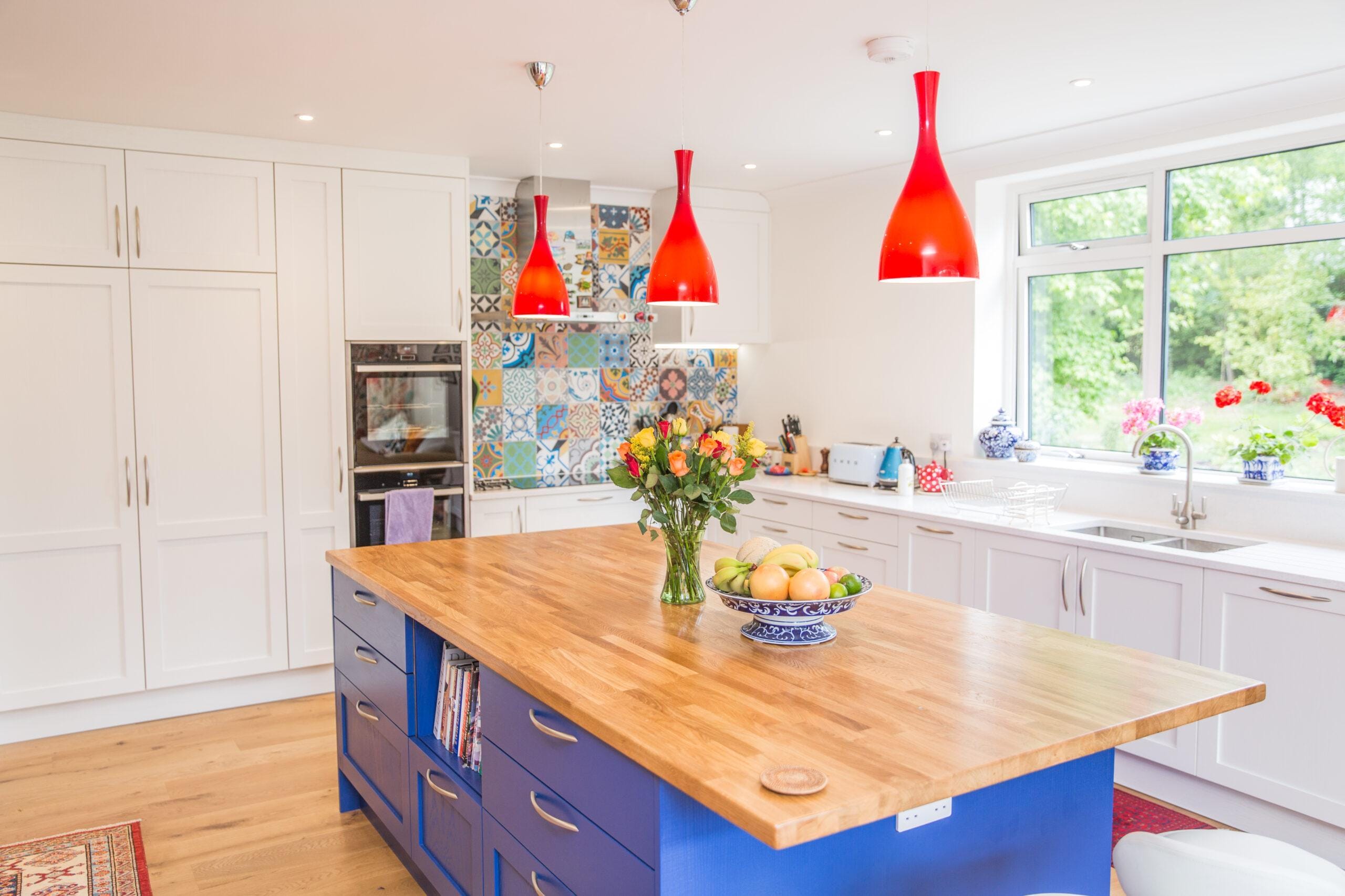 Bright Kitchen Living kitchen with blue island, timber worktop, red pendant lights and colourful open-plan design