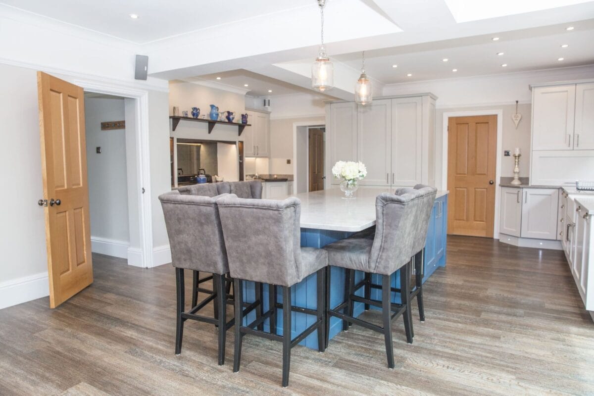 Open-plan bespoke kitchen with blue island, breakfast bar seating and family living space by Kitchen Living
