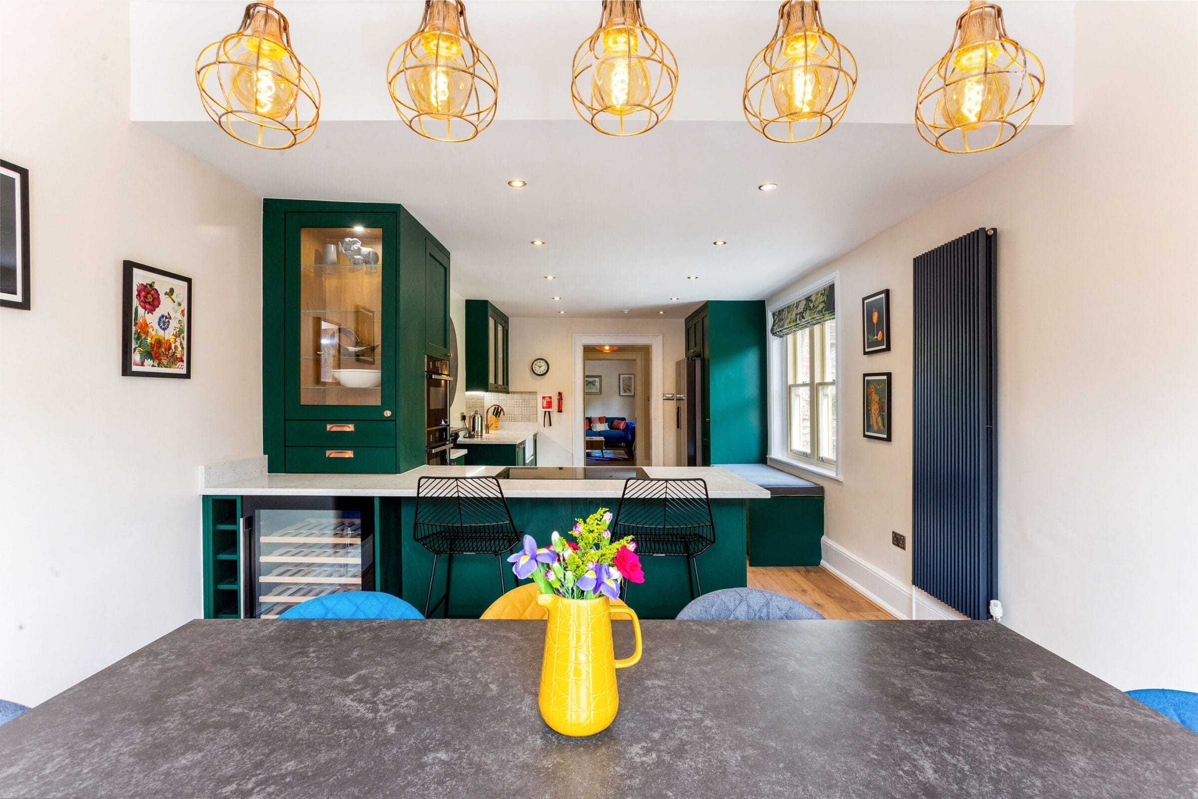 Open-plan kitchen and dining room with bi-fold doors, oak dining table and wood-effect flooring designed by Kitchen Living Winchester