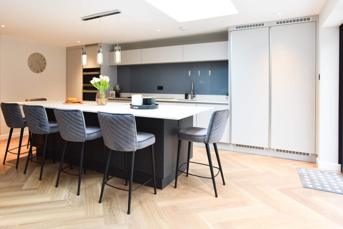 White and graphite handleless kitchen with large island, blue glass splashback and herringbone floor - Kitchen Living, Hampshire