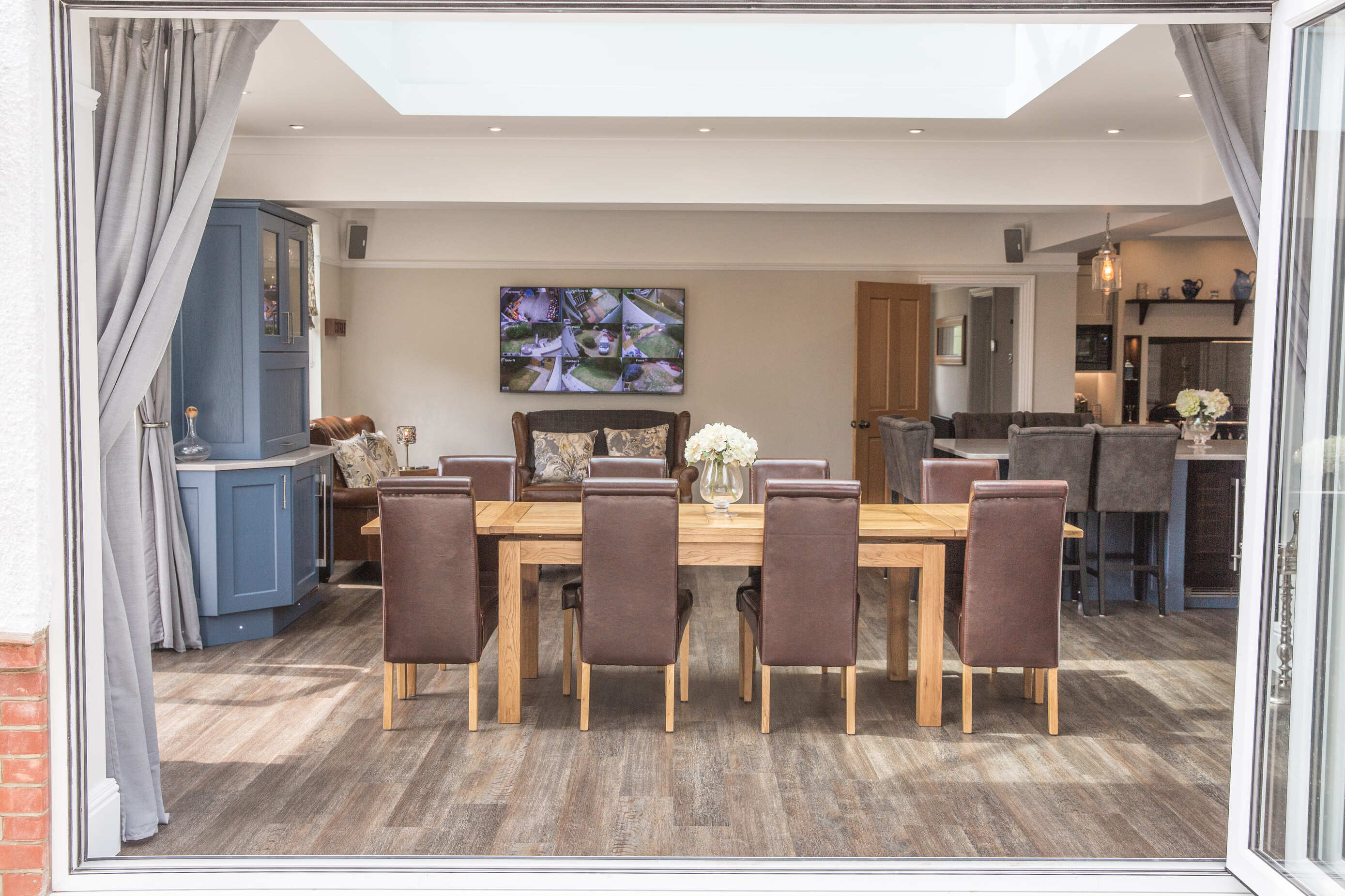 Open-plan kitchen and dining room with bi-fold doors, oak dining table and wood-effect flooring designed by Kitchen Living Winchester