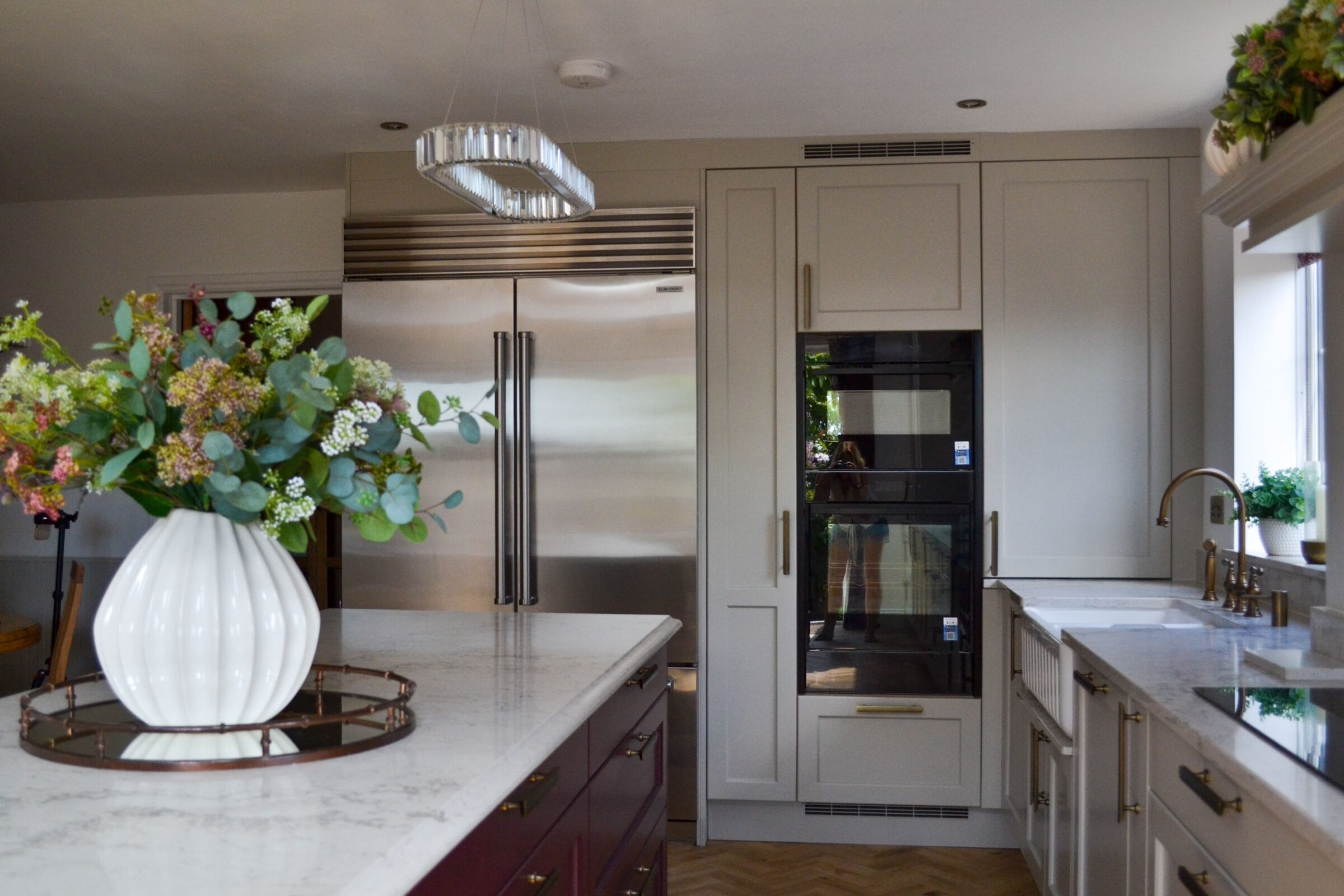 Light grey handleless kitchen with granite worktop, induction hob and industrial style pendant lighting by Kitchen Living