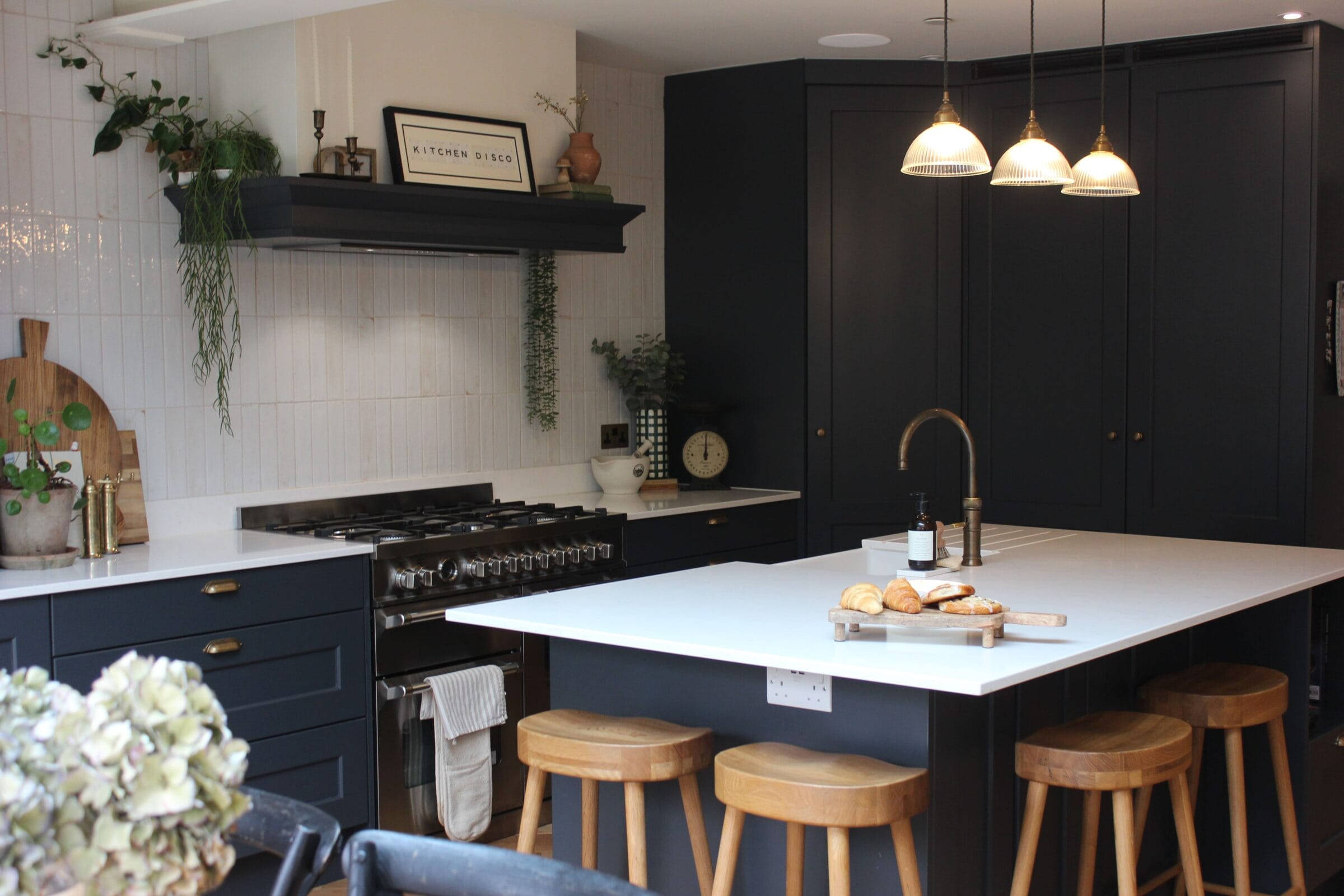 Modern dark blue shaker kitchen with white island, pendant lighting and wooden bar stools