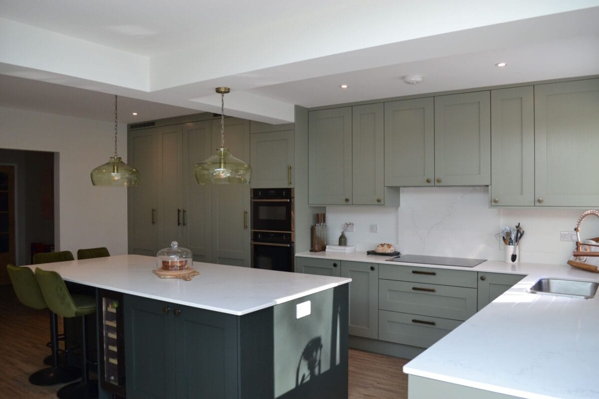 Bespoke shaker kitchen with sage green cabinetry and island seating by Kitchen Living