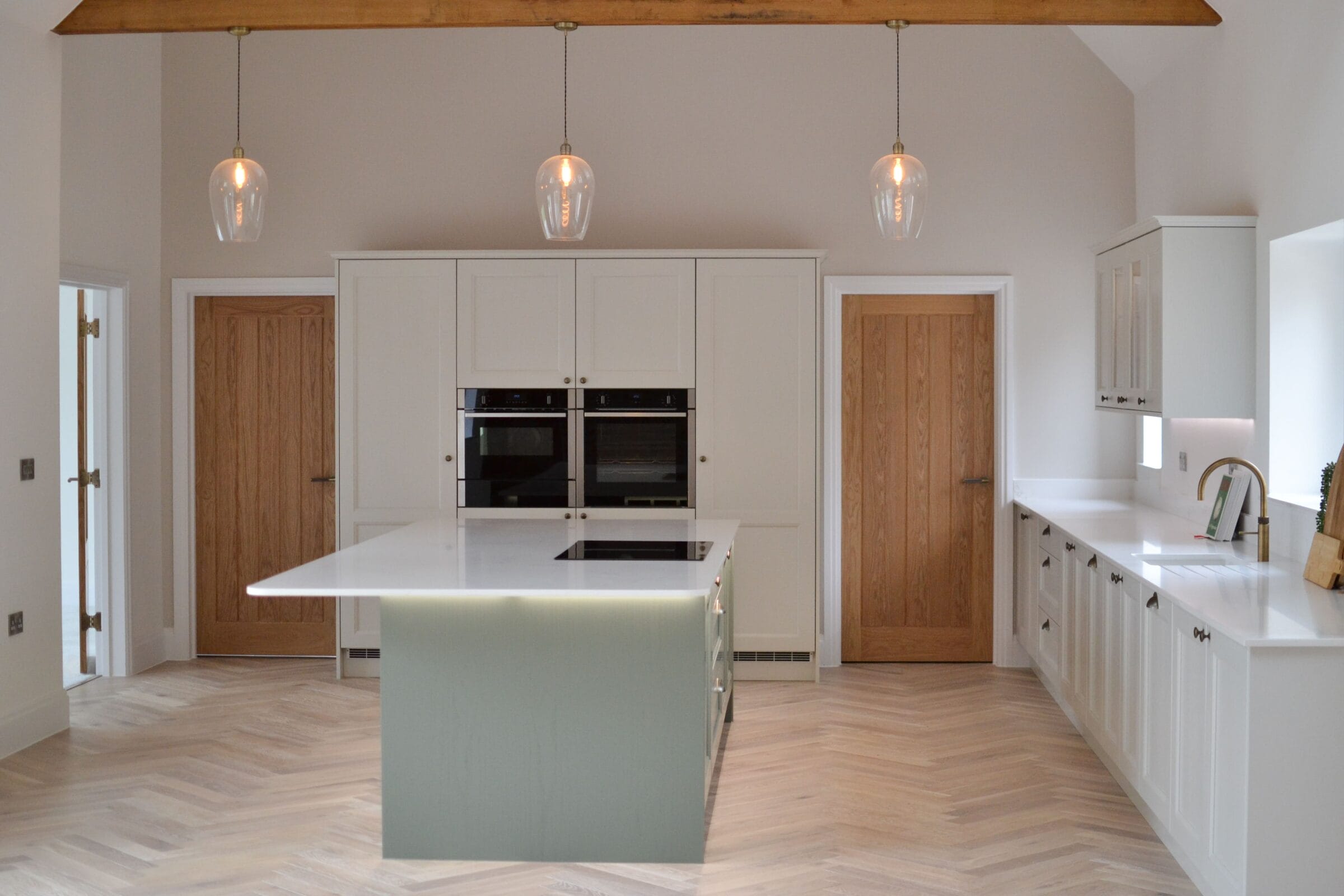 Contemporary Kitchen Living kitchen with soft green island, pale wood cabinetry, integrated ovens and pendant lighting