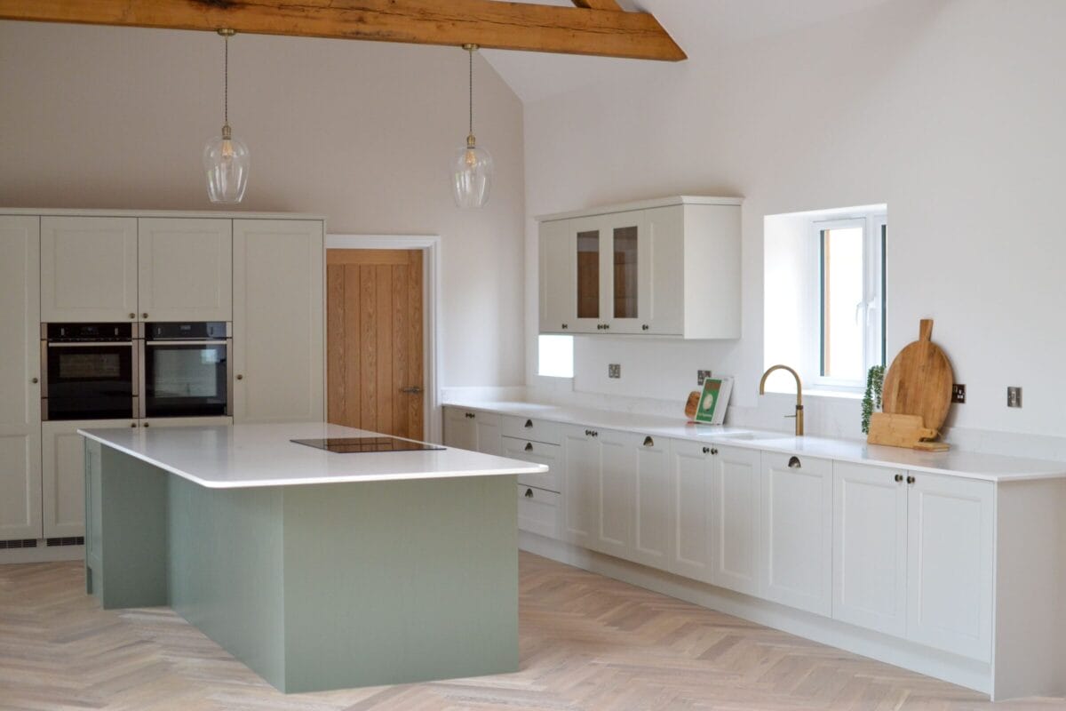 Contemporary shaker kitchen with sage green island, white cabinetry and vaulted ceiling beams